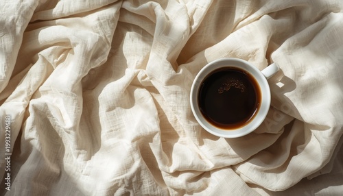 There is a cup of coffee sitting on top of a white cloth