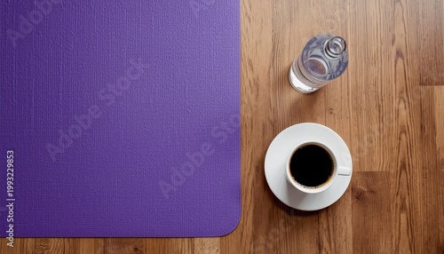 There is a cup of coffee next to a purple mat on a wooden floor