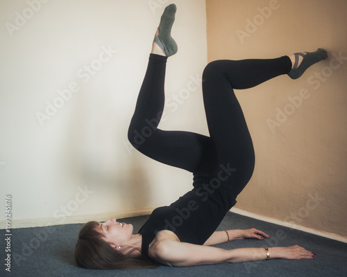 Принти на полотні Female athlete in sport wear performing supine core workout using wall for suppo