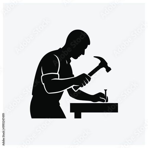 Black silhouette of a carpenter or worker using tools at a workbench.