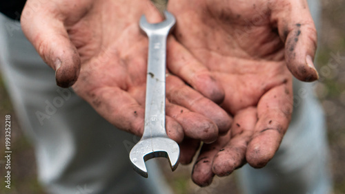 Cuadro en lienzo Greasy hands holding a metal wrench during mechanical work