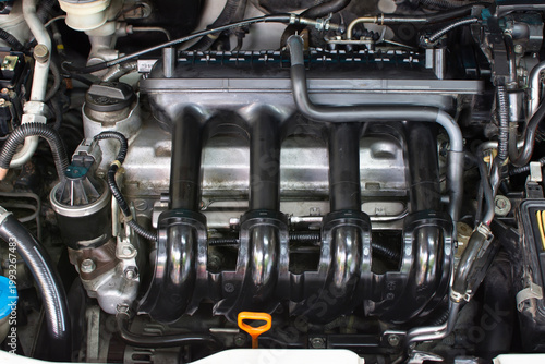 Car Engine Intake Manifold, A detailed view of a black plastic intake manifold assembly inside a car engine bay, vital for engine performance and air distribution.