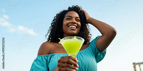 Curvy dark-skinned woman with long curly hair wearing a turquoise off-shoulder top, holding a yellow cocktail against a blue sky with white clouds.