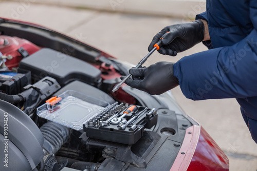Foto Man repairing car engine using tools under open hood during roadside maintenance