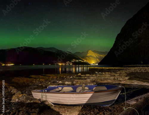 A bautiful aurora borealis display over boats in Norddal village harbor. A spectacular winter night scenery of Norway.