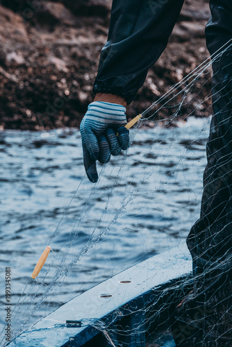 Fotografie Fisherman wearing gloves carefully handling fishing net during maritime work
