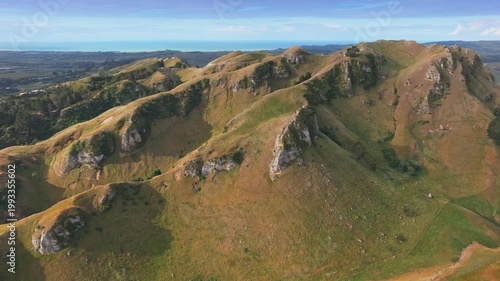 Rolling hills and valleys with rocky outcrops near the coast in Te Mata Peak, Havelock North, Hawkes Bay, New Zealand. The landscape is bathed in golden afternoon light.