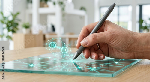 Designer uses digital pen on glass tablet to visualize hydrogen molecule structure for sustainable energy research work.