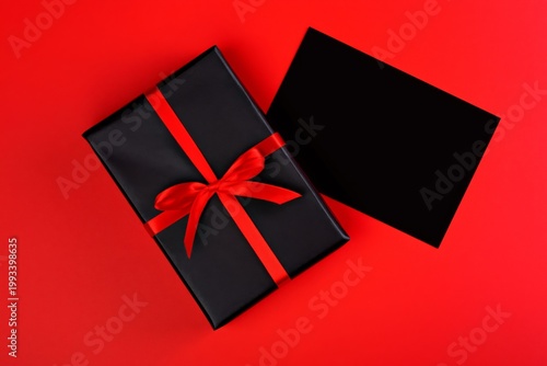 Gift Box Wrapped in Black With Red Ribbon on Red Background Ready for a Speci...