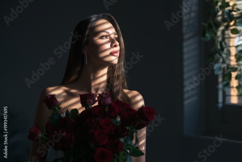 Woman Holding Red Roses in a Dark Room With Shadows and Light at Evening Time
