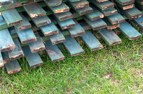 Konstfotografi Stack of old green painted wooden planks on green grass, construction materials