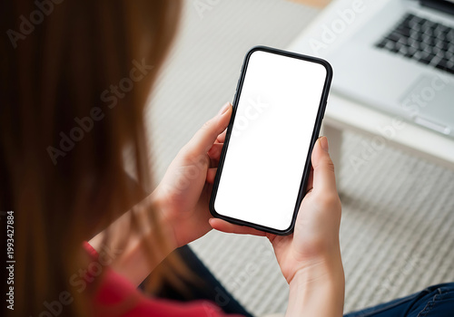 Woman using a smartphone next to a laptop