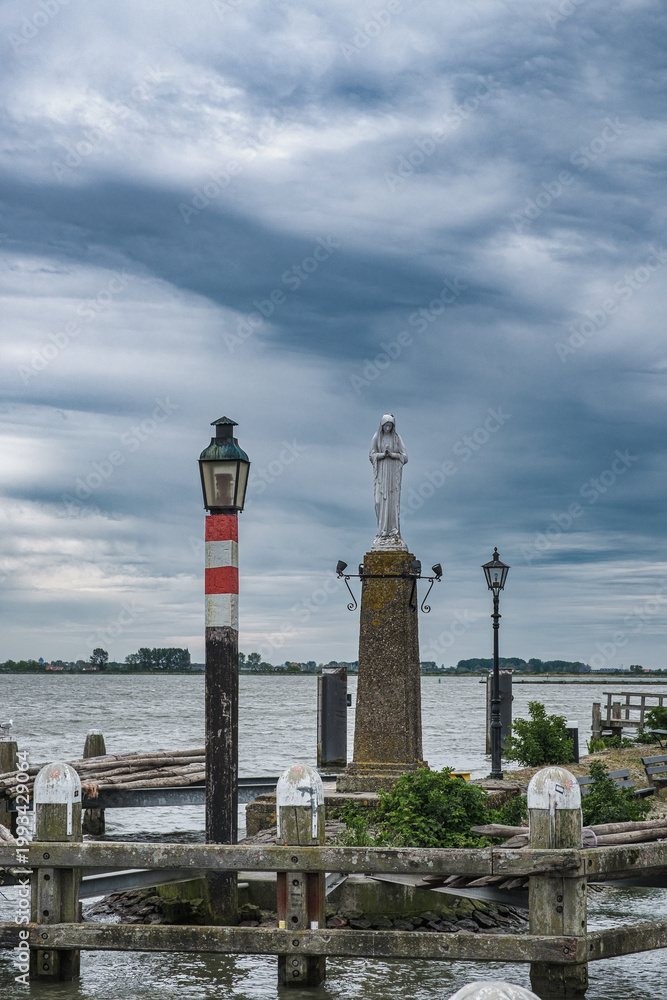 Fototapeta premium The statue of Mary at the harbor entrance in Volendam on the North Sea coast.