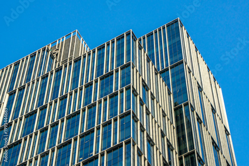 Billede på lærred Architectural detail of a modern urban building facade, featuring glass windows and striking frame lines that create an interesting geometric pattern