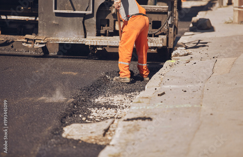 Construction workers working on a new asphalt layer on a public street.