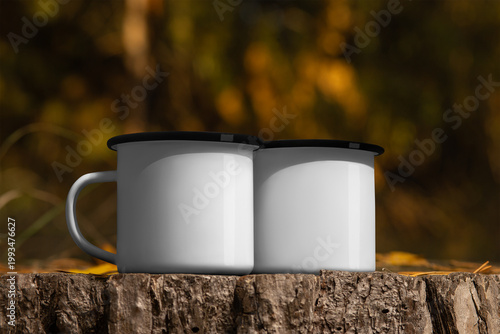 Mockup of enameled white mugs with black rim, set of iron dishes on wood log, on nature background, outdoors.