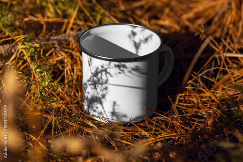 Mockup of enameled white mug with iron rim, handle, with shadows from branches, on a background of pine needles, nature, outdoors.