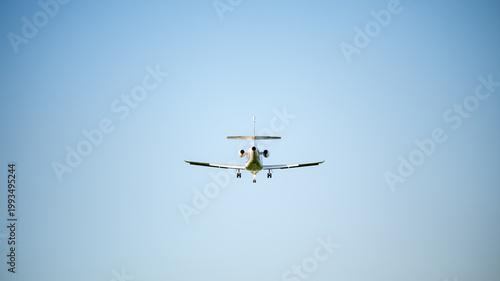 Passenger airplane approaching for landing against clear sky, front view