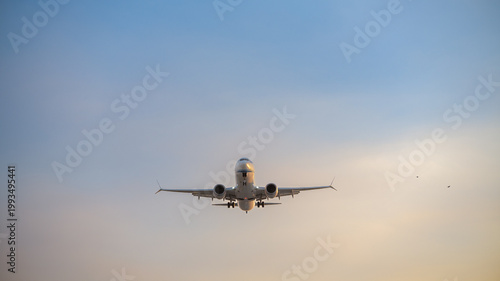 Passenger airplane approaching for landing against clear sky, front view