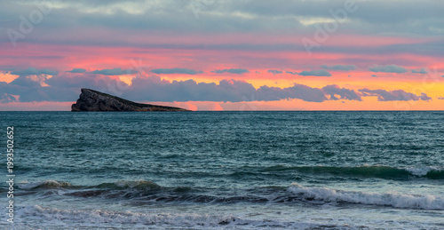 Isla de Benidorm rocky Island landscape rising from Mediterranean Sea waters at sunset golden hour seen from Poniente Beach at Costa Blanca coast of Benidorm in Spain