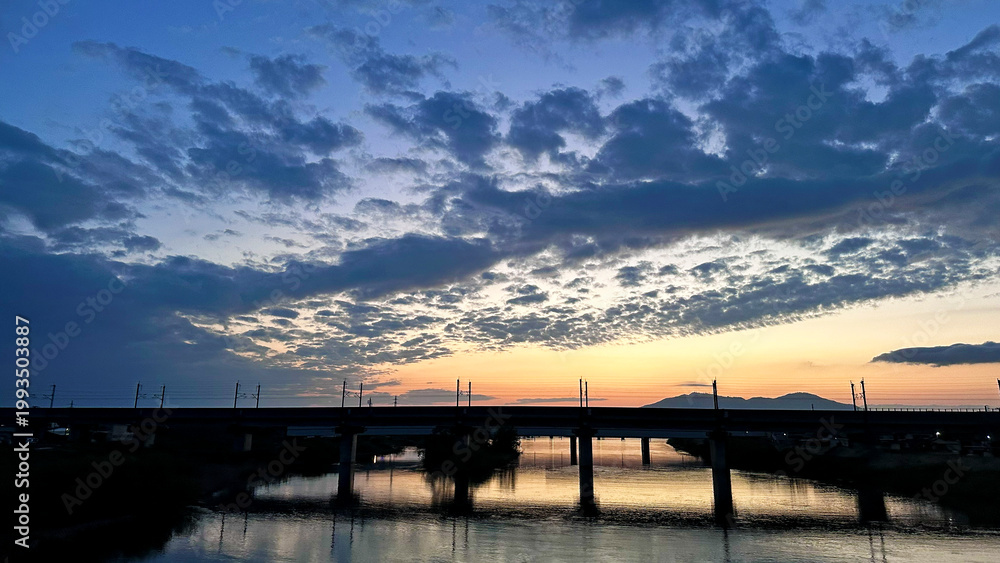 Obraz premium 新潟県燕市 中ノ口川の夕暮れ 佐渡橋から望む鉄道橋と美しい空の風景
