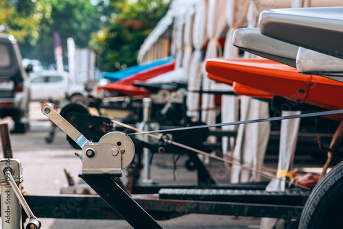 Manual Hand Winch on Boat Trailer with Strap and Rusty Details. Close up of Mechanical Winch Mechanism for Boat Transport and Hauling. Metal Boat Trailer Frame with Manual Crank Winch Equipment.
