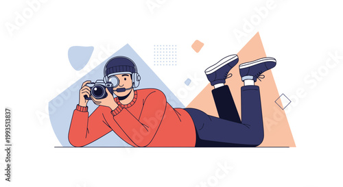 Creative photographer lying down with camera, abstract geometric background