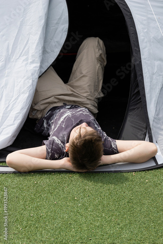 Fotografie boy resting in tent camping background gray fabric surface teenage boy looking a