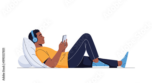 Young man relaxing on a pillow while listening to music through headphones and using a smartphone on the floor.