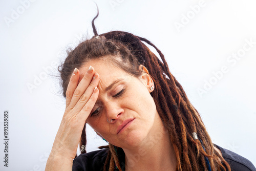 Stressed woman with dreadlocks holding head overwhelmed by anxiety