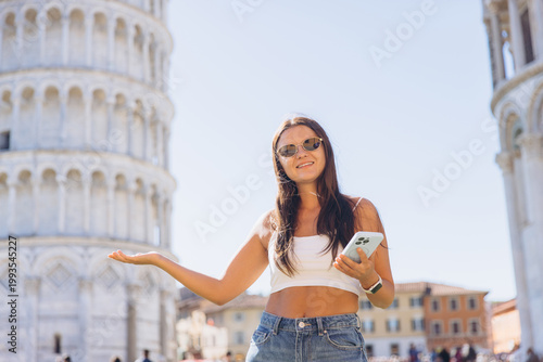 Young woman presenting at the Leaning Tower of Pisa, traveling Italy during summer vacation