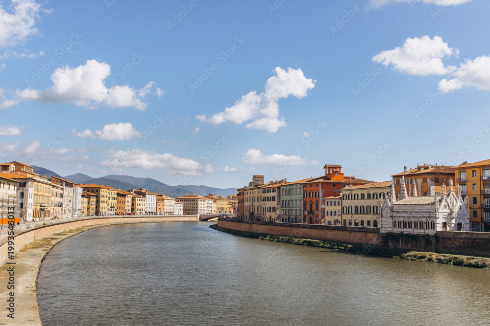 Fototapeta premium Arno river flowing through Pisa, Italy with historic buildings and Santa Maria della Spina chapel along the bank