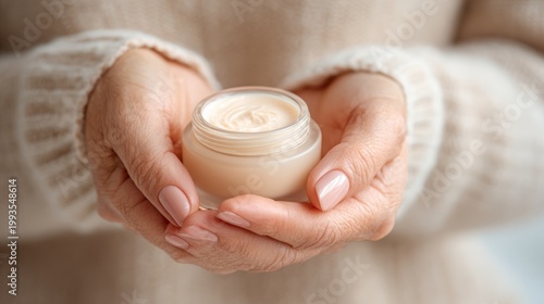 Woman holding jar of cream with soft sweater in a cozy setting