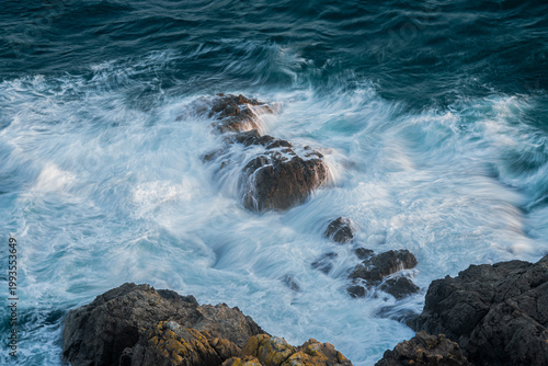Powerful ocean waves crashing against rugged rocks on the Guernsey  coastline. Dynamic seascape capturing the raw energy and force of nature.