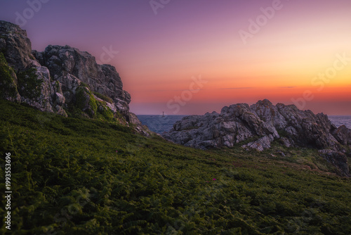 Moody twilight seascape with deep purple and red tones over the rocky coastline of Guernsey. Cinematic atmosphere capturing mystery and emotional depth.