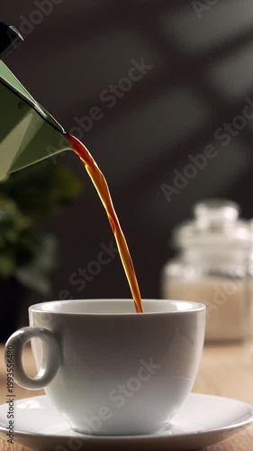 Pouring a hot morning coffee from a moka pot in white cup. Concept of Start to day
