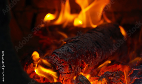 Close-up of burning firewood in a fireplace with bright orange flames.