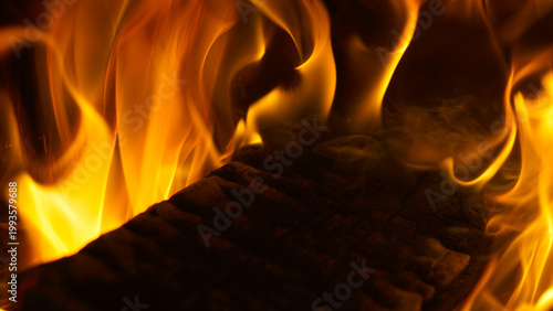 Horizontal close-up of intense orange fire flames burning over wood