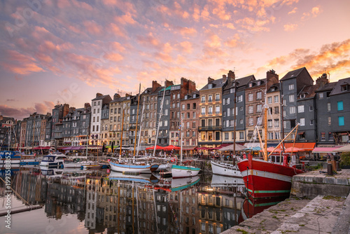 View of Honfleur old port under dramatic sky at sunset in summer. Reflection in water.