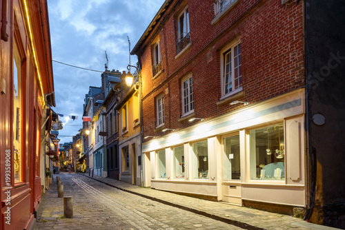 Narrow cobbled street lined with traditional buildings and colourful shops at dusk in summer
