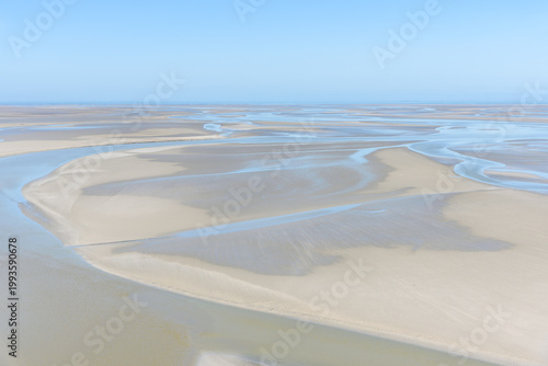 Stretch of tidal mudflats on the coast of Normandy under clear blue sky in summer