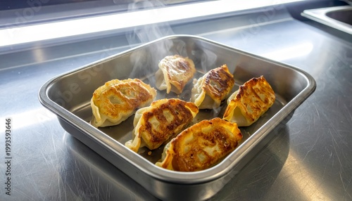 Golden brown pan-fried dumplings, perfectly seared and steaming in a metal tray