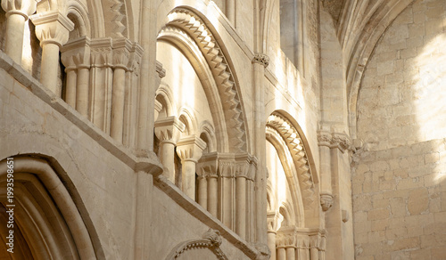 Fotografija Romanesque church interior with arches, columns and warm sunlight