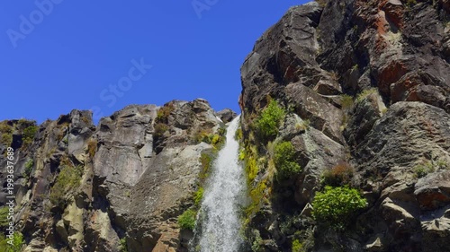 Scenic view of Taranaki Falls dropping into a clear pool surrounded by rocks and lush bush