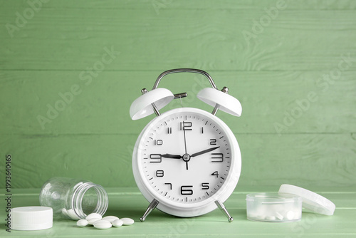 Pills and alarm clock on gr...