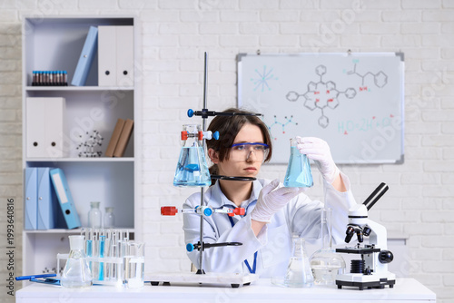 Female scientist with flask examining water quality at table in laboratory