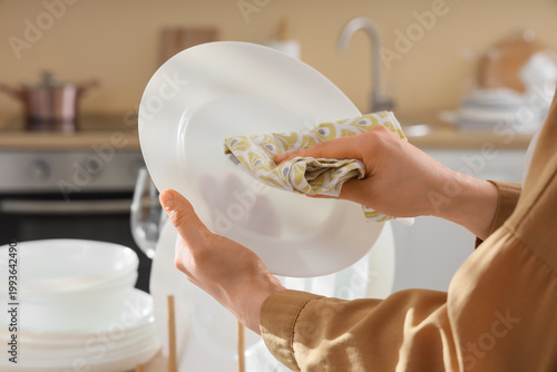 Fotografía Female hands wiping plate in kitchen, closeup