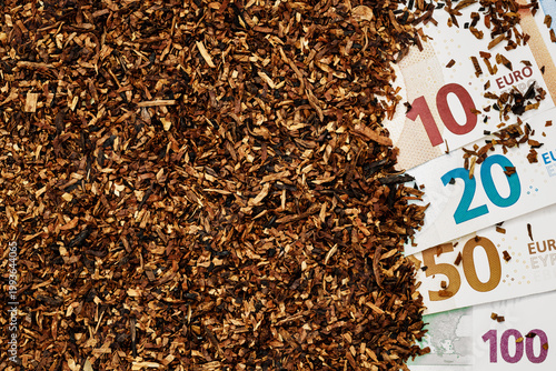 Various euro banknotes next to chopped tobacco on a flat surface in a well-lit setting