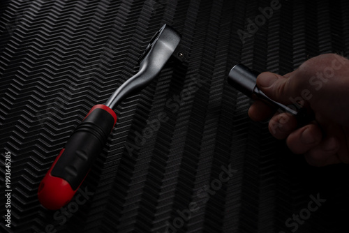 Foto Hand holding socket preparing to attach ratchet wrench on dark textured backgrou