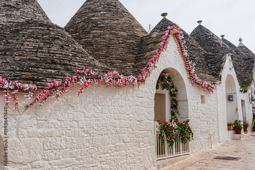 Fototapeta premium Alberobello miasto we Włoszech, słynie z unikatowych form budownictwa – domów typu trulli, które są okrągłe i mają stożkowate dachy z kamienia.